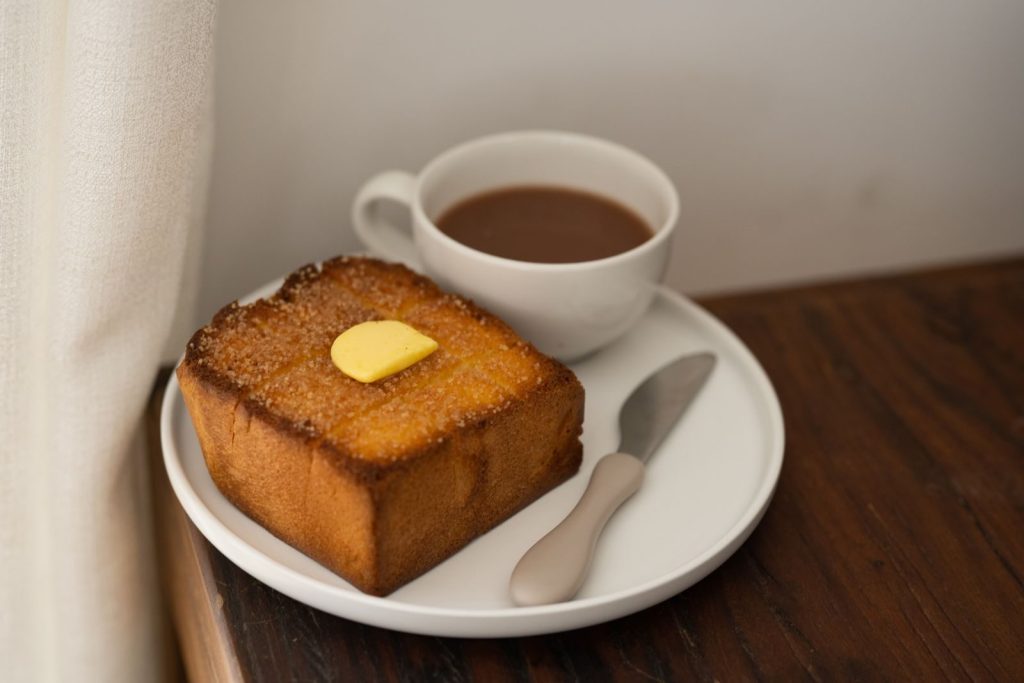 A cozy breakfast setting featuring toasted bread with butter and a cup of coffee on a wooden table.