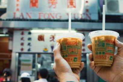 Two people holding up drinks in front of a restaurant