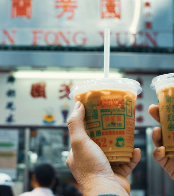 Two people holding up drinks in front of a restaurant
