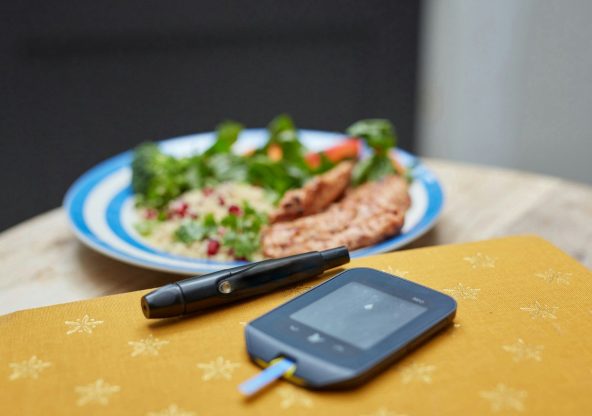 a plate of food and a Glucometer on a table