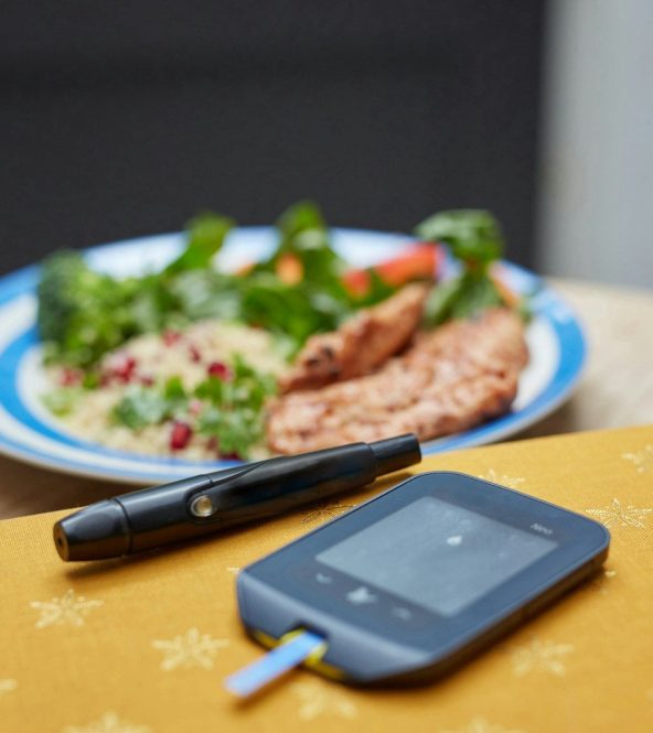 a plate of food and a Glucometer on a table