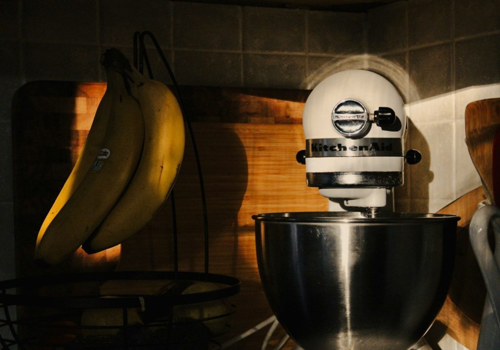 a white mixer sitting on top of a counter next to bananas