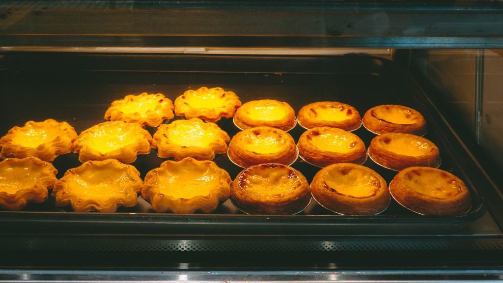 Freshly baked egg tarts are displayed in a case.